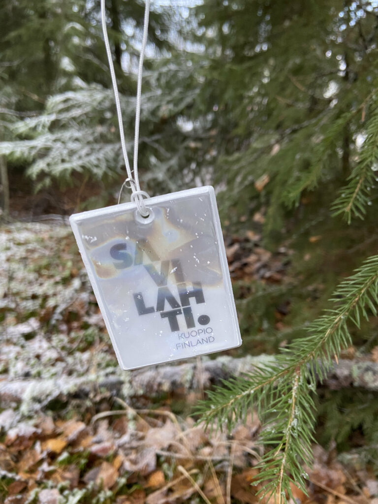 Lumisen havupuun oksaan sidottu neliskanttinen heijastin, jossa teksti "SAVILAHTI."